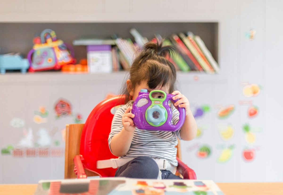 A toddler playing with a toy camera at playgroup