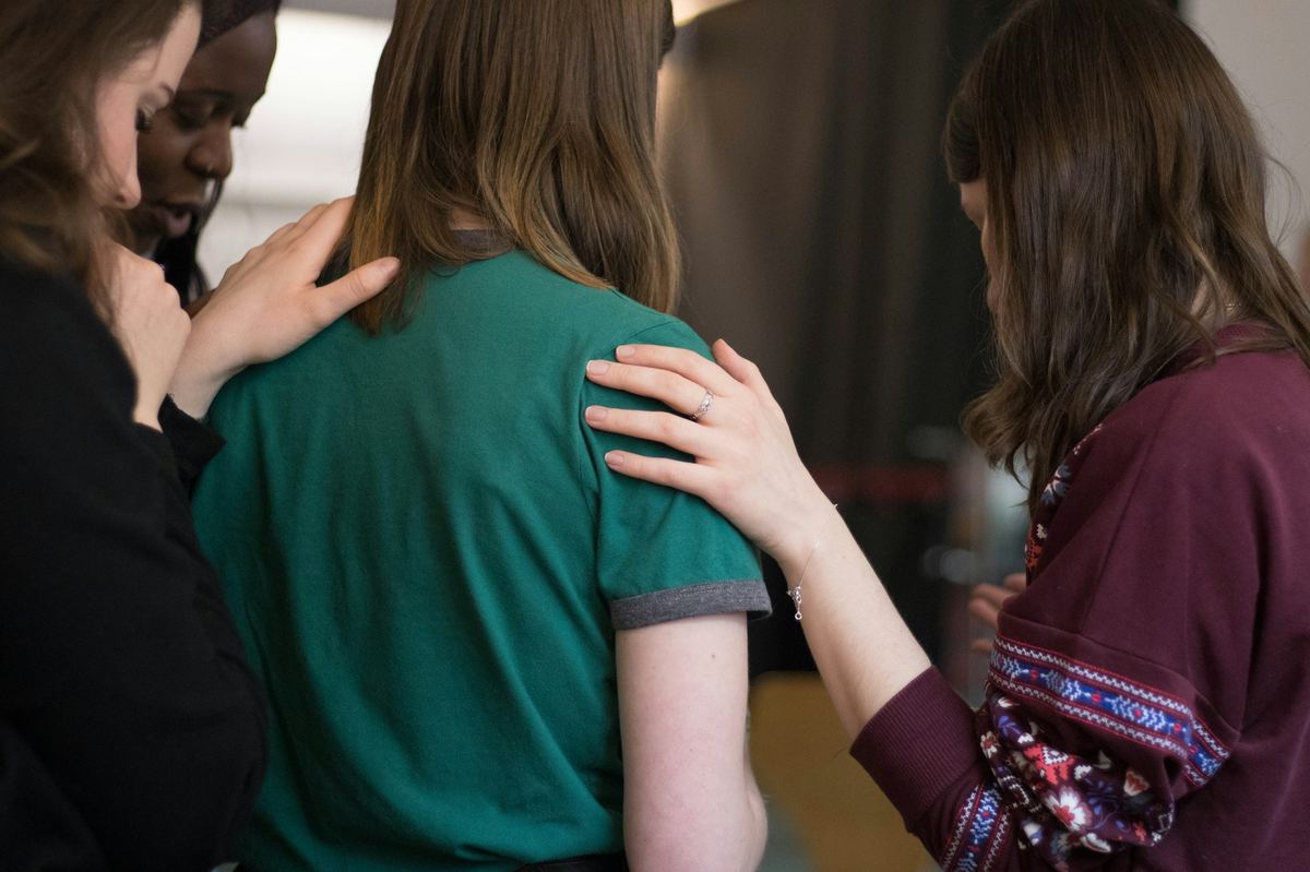 Church members praying with and comforting a person in need