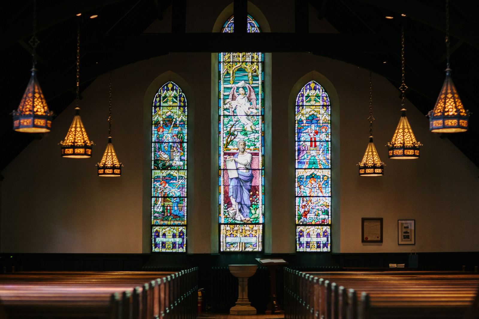 Stained glass windows glowing inside a church sanctuary